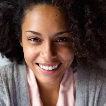 Close-up of a smiling woman with curly hair looking up at the camera.