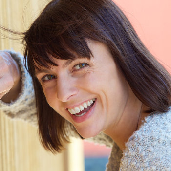Smiling woman leaning against a wall.