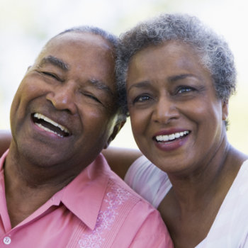 Elderly couple smiling together outdoors.