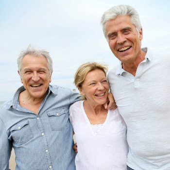 Three older adults smiling outdoors.