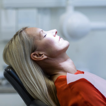 Woman reclining in a dental chair, awaiting a check-up or procedure.