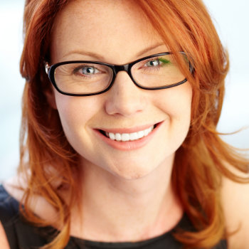 Smiling woman with red hair wearing glasses.