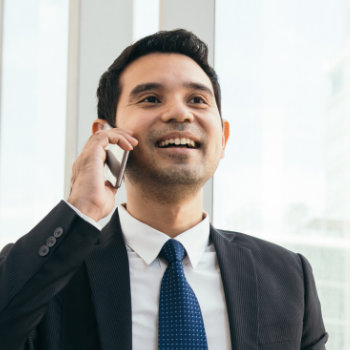 Professional man in a suit smiling while talking on a cellphone.