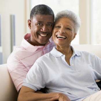 A smiling elderly couple embracing and looking content.