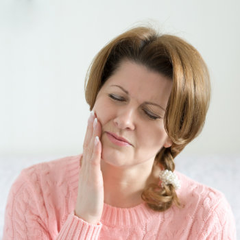 A woman holding her cheek, appearing to be in discomfort or pain.