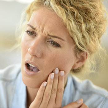 Woman experiencing toothache and holding her jaw.