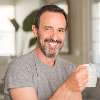 Man smiling while holding a mug indoors.