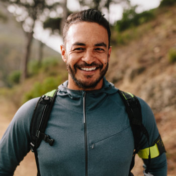 Smiling man with a backpack enjoying a hike outdoors.