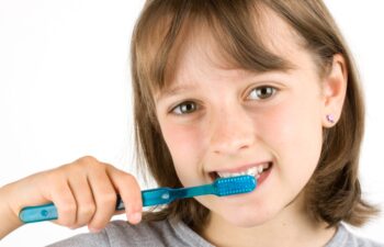 Girl brushing her teeth against a white background